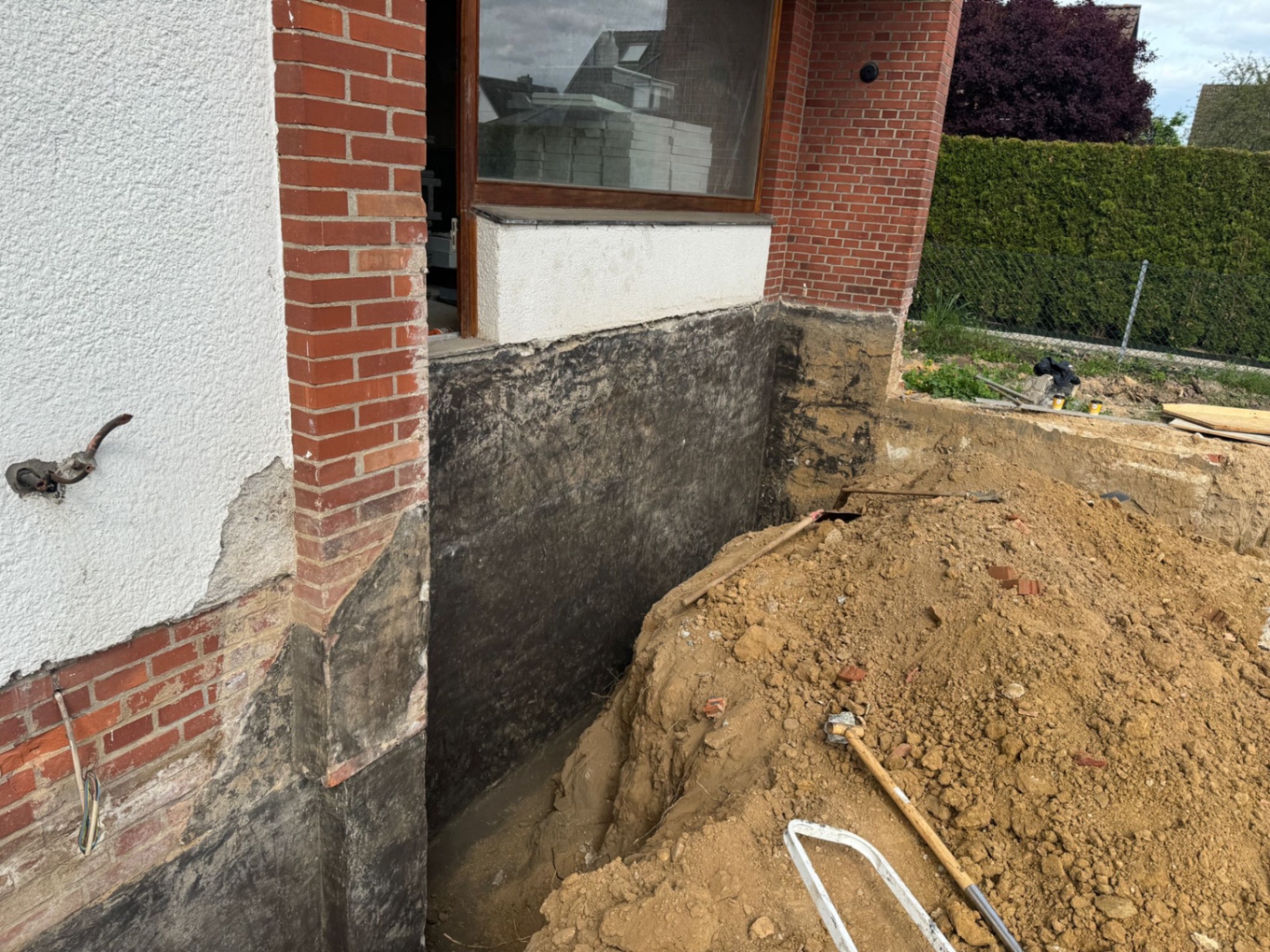 Freigelegte Hauswand mit Erdarbeiten und Abdichtung